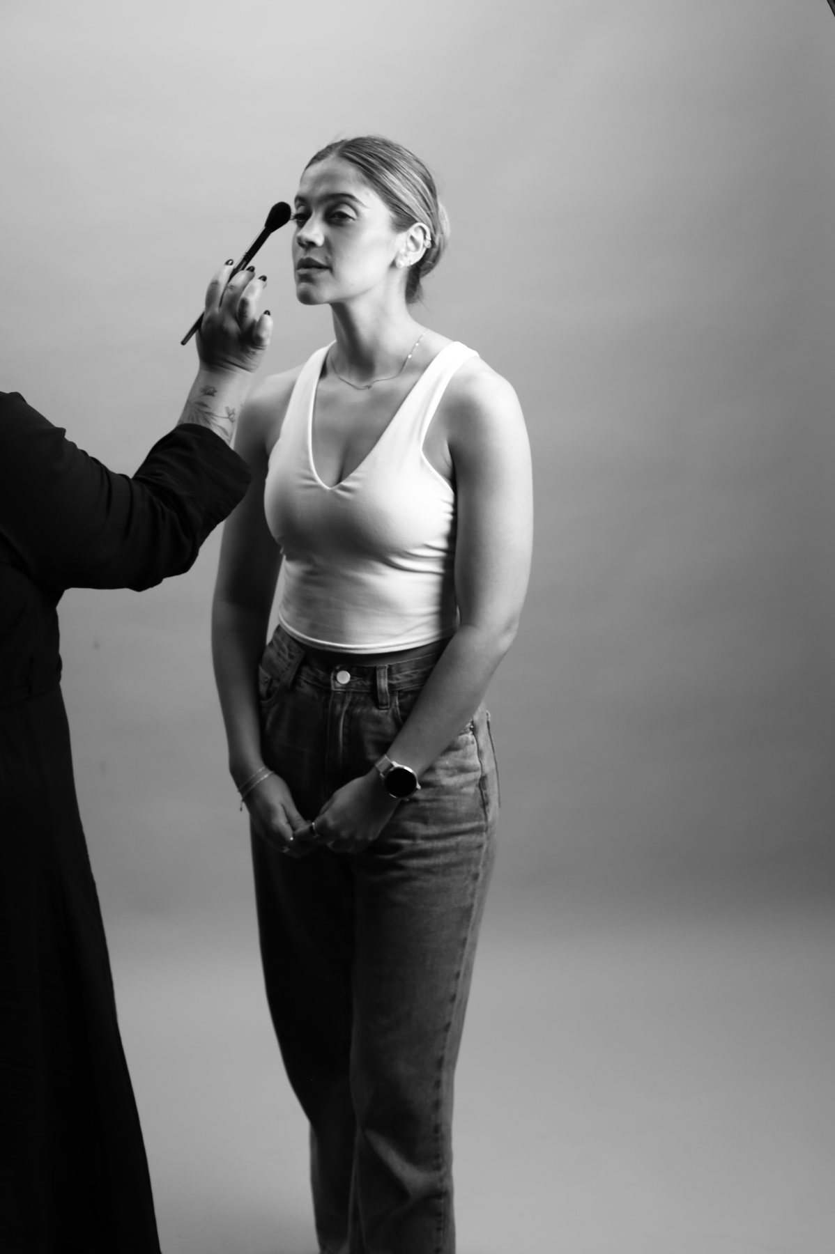Lulu maquillando a una modelo en estudio, en blanco y negro