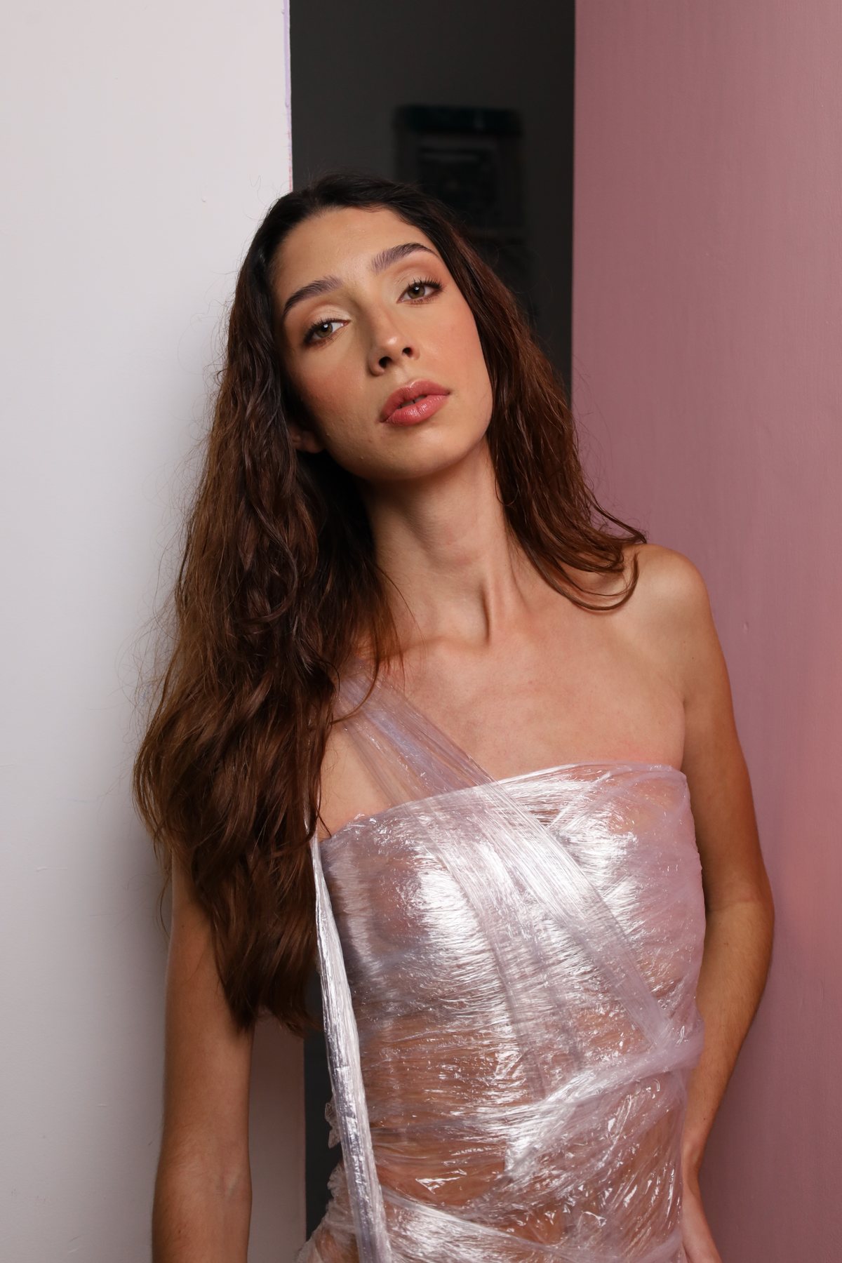 Modelo con cabello largo frente a pared rosa